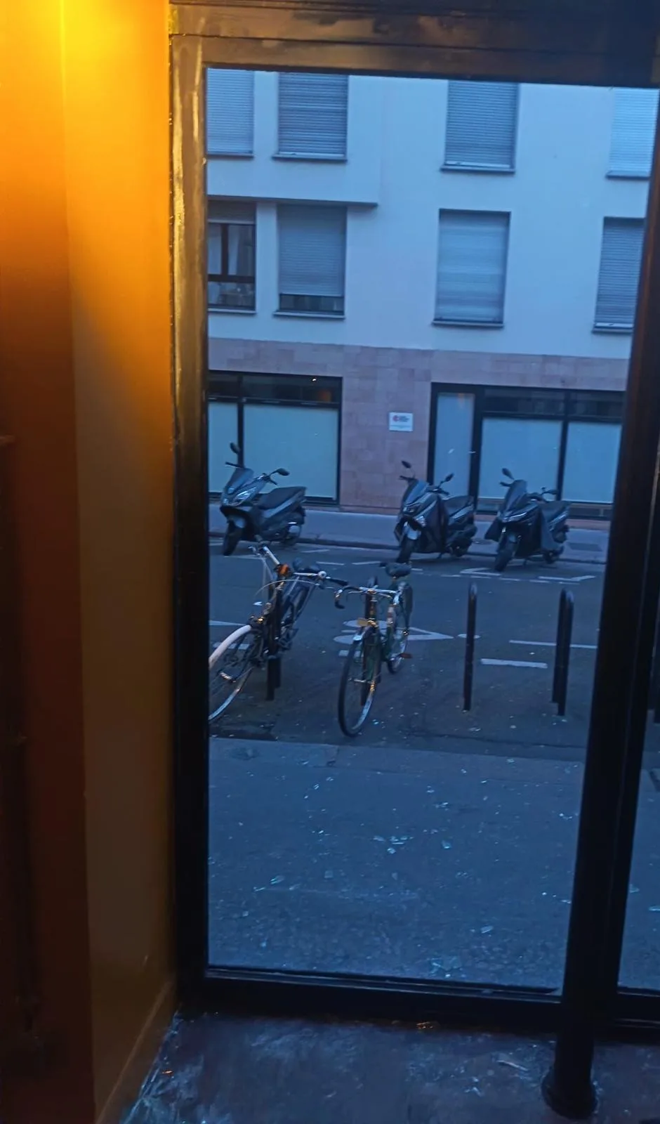 Baie de vitrine vide après dépose du vitrage brisé, éclats de verre restant sur le trottoir